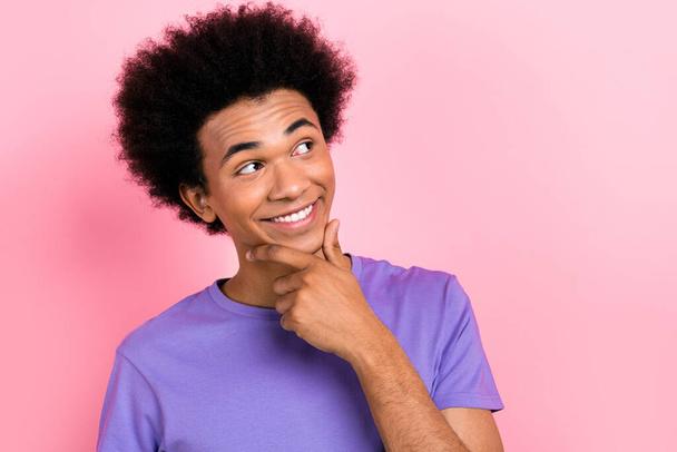 Photo of minded man with afro hairstyle dressed blue t-shirt fingers chin look at dental ad empty space isolated on pink color background. - Photo, Image