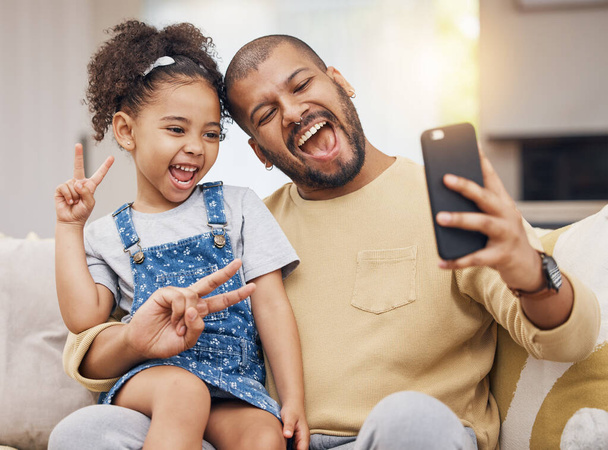 Father, girl and peace sign selfie in home living room, bonding and funny together. Dad, child and excited in v hand on profile picture, happy memory or social media post of family laughing on sofa. - Zdjęcie, obraz