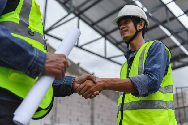 Close-up hand van Civil Engineer met contractanten schudden hun handen in de bouw gebouw, overeenkomst van de partners in het contract. Handdruk van civiel ingenieur business concept. - Foto, afbeelding