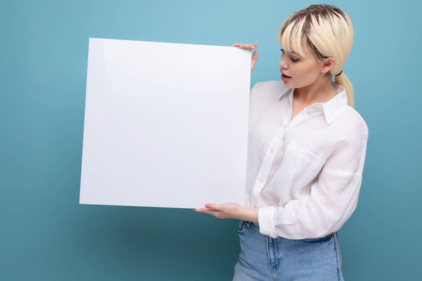 jong mooi blond student vrouw gekleed in een wit blouse demonstreert haar studie project op een schoolbord met een mockup. - Foto, afbeelding
