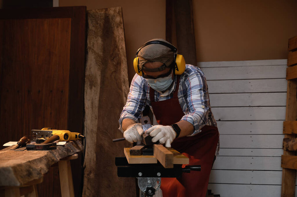 Timmerman die hard werkt tijdens het schaven op hout met een handmatige houtschaafmachine of vliegtuiggereedschap in een houtwerkplaats of timmerwerkplaats, Ambacht, Handyman concept - Foto, afbeelding