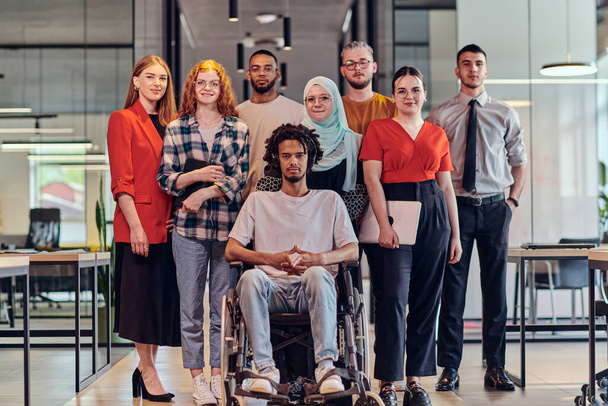 A diverse group of young business people congregates within a modern startups glass-enclosed office, featuring inclusivity with a person in a wheelchair, an African American young man , and a hijab - Valokuva, kuva
