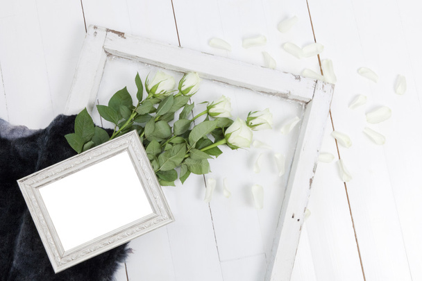 Empty picture frame with white roses, fallen petals and blue-grey fur - Photo, Image