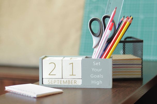 21 вересня. Зображення 21 вересня дерев'яного календаря на стільниці. Осінній день. Повернутися до школи. Олівці та фарби, канцелярські товари - Фото, зображення