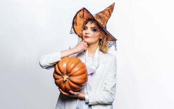 Smiling woman in witch hat with pumpkin. Halloween holiday. Halloween witch with Jack-o-lantern pumpkin. Attractive girl preparing for Halloween. Female model with magic pumpkin celebrating Halloween - Photo, Image