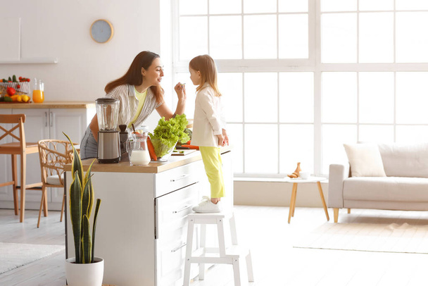 Petite fille avec sa mère cuisine salade saine dans la cuisine - Photo, image