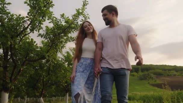 Onnellinen valkoihoinen pariskunta pitelee toisiaan kädestä ja kävelee ulkona maaseudulla. Kesälomat, rakkaus, romantiikka ja ihmisten käsite. - Materiaali, video