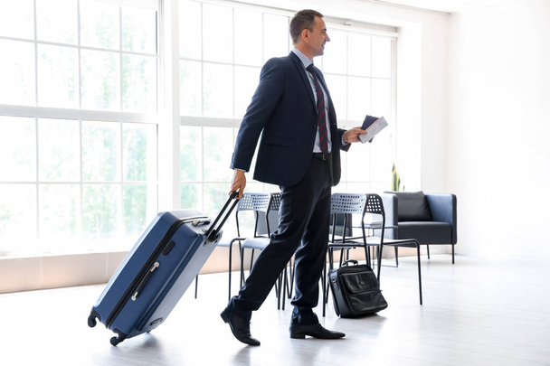 Rijpe zakenman met koffer lopen in de hal van de luchthaven - Foto, afbeelding