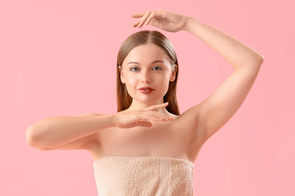 Pretty young woman wrapped in towel on pink background - Photo, Image