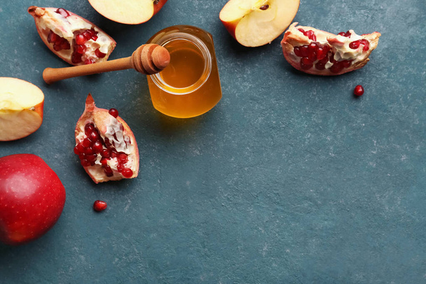 Tarro de miel con granada y manzanas para la celebración de Rosh Hashaná (Año Nuevo judío) sobre fondo azul - Foto, Imagen