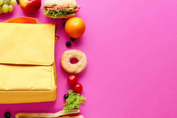 Bolsa lonchera con diferentes sabrosos alimentos sobre fondo rosa - Foto, imagen