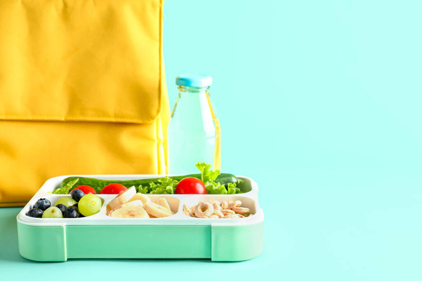 Sac, bouteille d'eau et lunchbox avec de la nourriture savoureuse sur fond turquoise - Photo, image