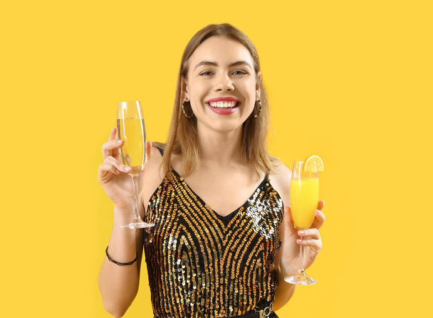 Schöne junge Frau mit verschiedenen Cocktails auf gelbem Hintergrund - Foto, Bild