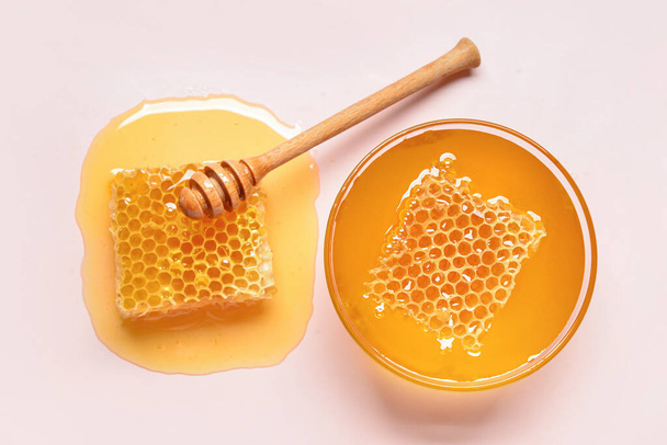Üvegtál édes méz és fésűk rózsaszín alapon - Fotó, kép