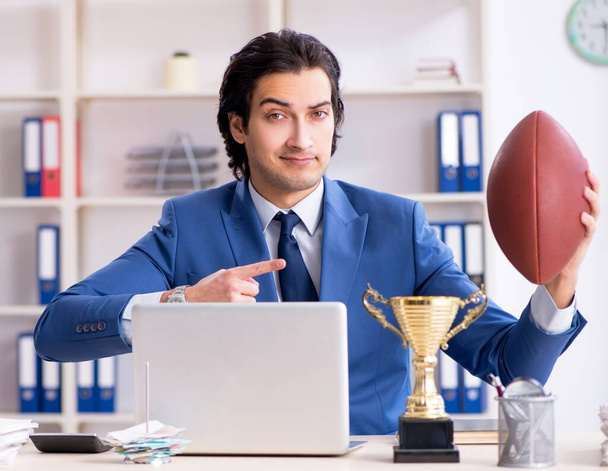 Le jeune homme d'affaires beau avec ballon de rugby dans le bureau - Photo, image