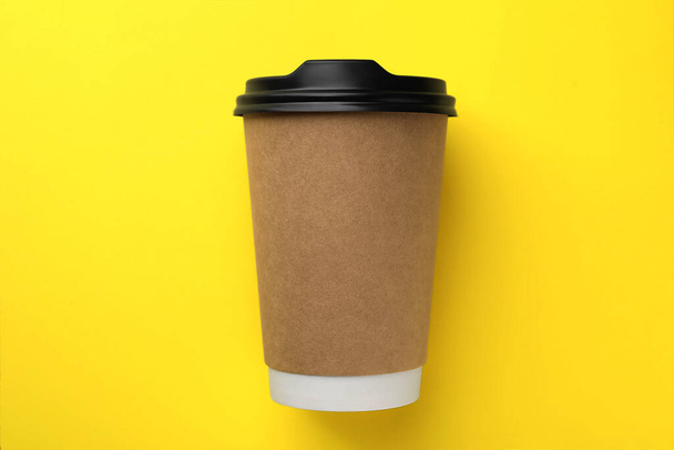 One paper cup on yellow background, top view. Coffee to go - Photo, image
