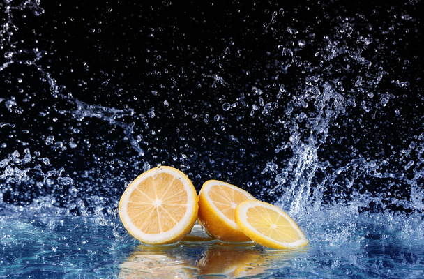 Sliced lemon in the water on black background - Photo, Image