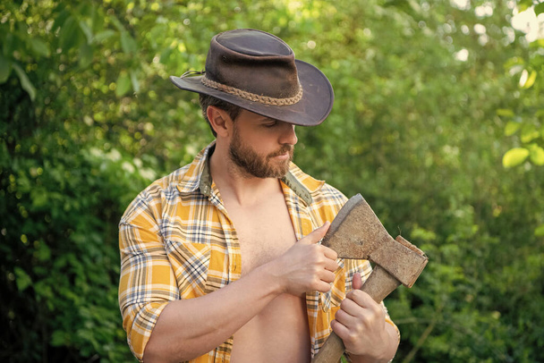 photo of rancher man with axe. rancher with axe. rancher with axe wearing checkered shirt. rancher with axe outdoor. - Foto, Imagem