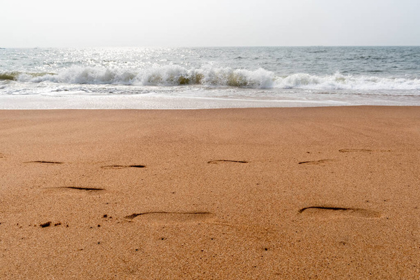 Voetstappen op het zand naast de zee aan het prachtige strand in Sinquerim in Goa. - Foto, afbeelding