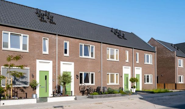 Holenderska okolica z nowoczesnymi domami rodzinnymi, nowo wybudowane nowoczesne domy rodzinne w Holandii, holenderski dom rodzinny w Holandii, ulica z nowoczesnymi domami rodzinnymi na miejskich przedmieściach  - Zdjęcie, obraz