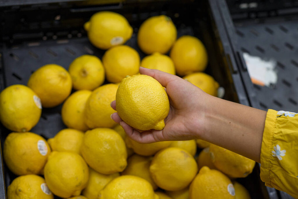 Persona sosteniendo un limón en un supermercado. - Foto, imagen