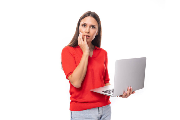 ritratto di una donna bruna di successo con i capelli lisci in una t-shirt rossa e jeans con un computer portatile di lavoro. concetto di e-business. - Foto, immagini