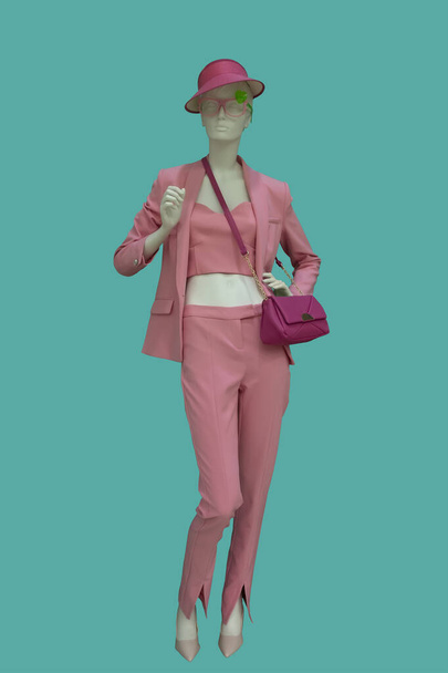 Volledige afbeelding van een vrouwelijke etalagepop in trendy roze broek geïsoleerd op blauwe achtergrond - Foto, afbeelding
