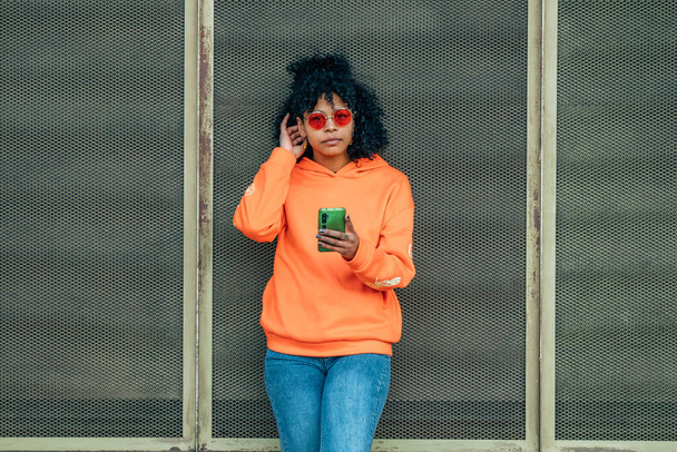 чорна жінка з мобільним телефоном на вулиці - Фото, зображення
