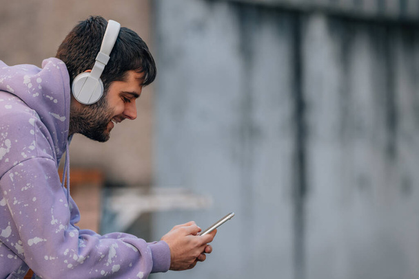 urban young man with mobile phone or smartphone and earphones in the street - Fotografie, Obrázek