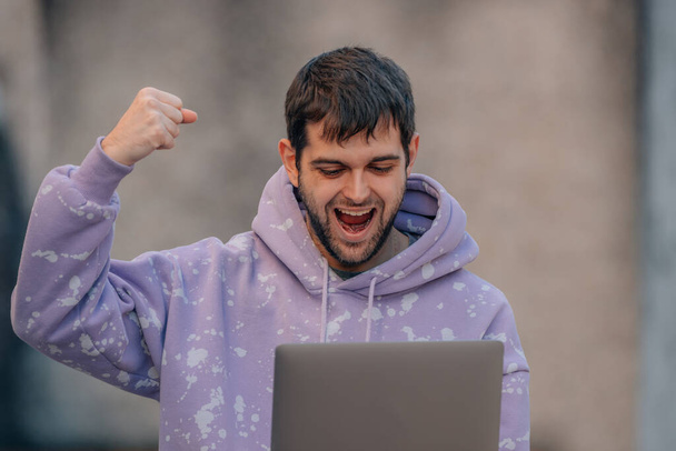 młody człowiek z laptopem na ulicy z wyrazem sukcesu - Zdjęcie, obraz