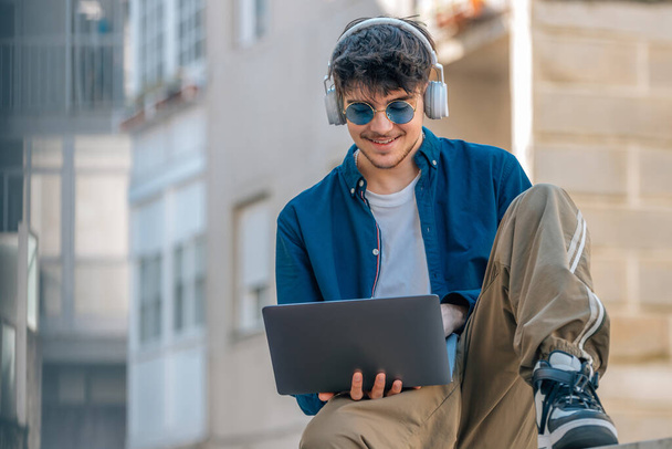 young man in the street with laptop and sunglasses - Photo, Image