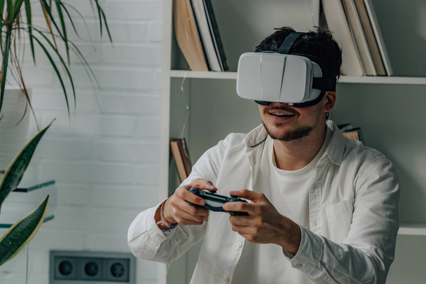 jeune homme à la maison avec joystick et lunettes de réalité virtuelle, jeux - Photo, image