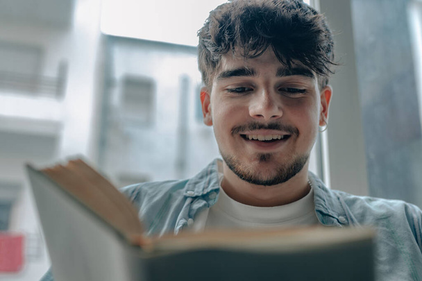 νεαρός άνδρας που διαβάζει ένα βιβλίο ή σπουδάζει στο σπίτι - Φωτογραφία, εικόνα