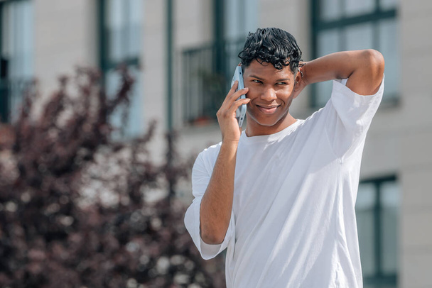 joven latino macho en la calle hablando por teléfono móvil - Foto, imagen