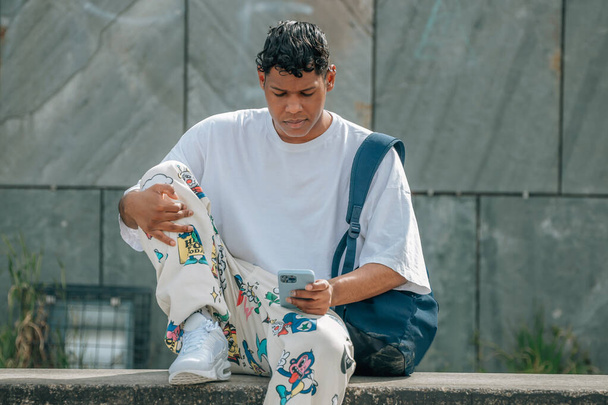 joven latino con teléfono móvil en la calle - Foto, Imagen