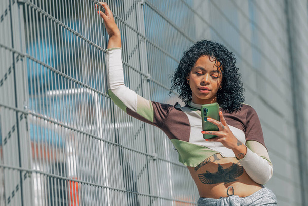городская девушка на улице смотрит на мобильный телефон - Фото, изображение