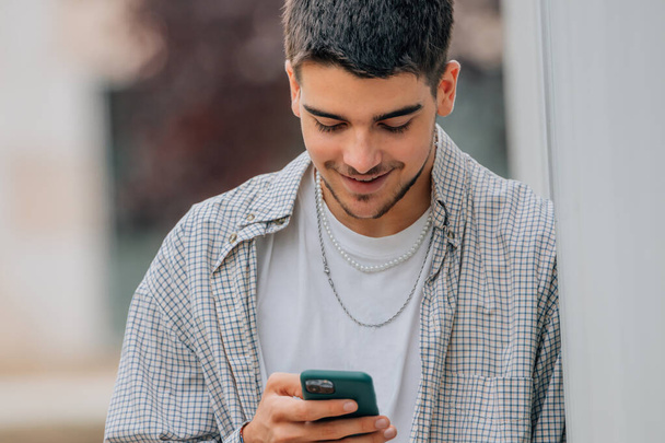 teenager chlapec na ulici při pohledu na mobilní telefon - Fotografie, Obrázek
