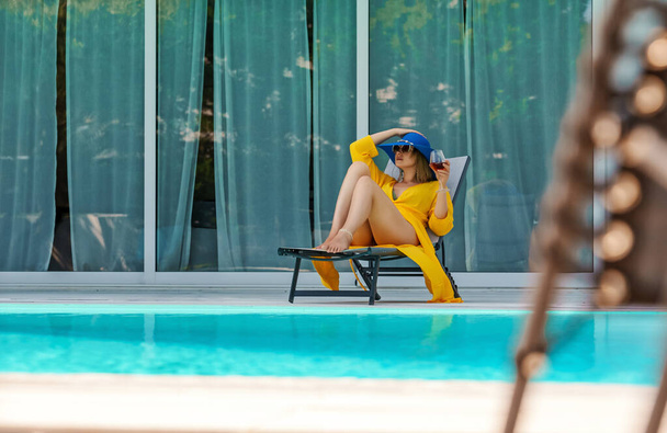 Mujer con copa blanca de vino relajante cerca de la piscina. - Foto, Imagen