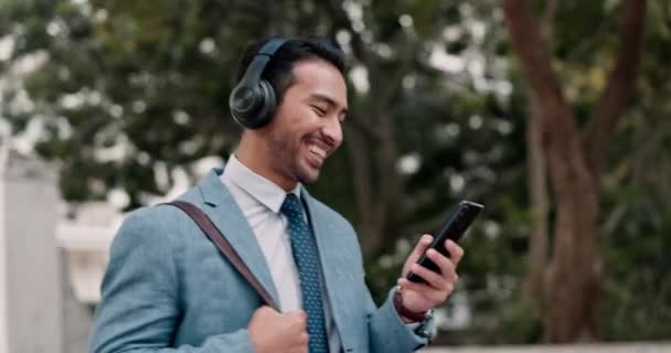 Kulaklıklar, telefon ve iş adamı şehirde yürüyor müzik dinliyor ve sosyal medyada iletişim kuruyor. Mutluluk, gülümseme ve parka gidip gelen cep telefonlu profesyonel erkek çalma listesi. - Video, Çekim