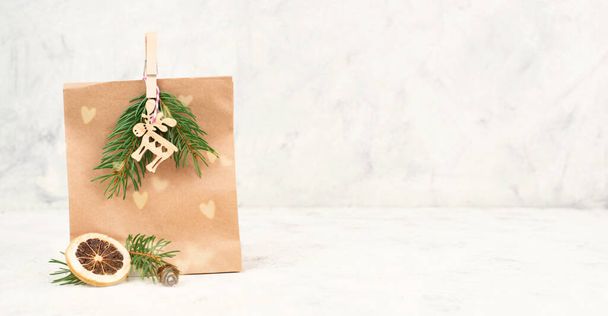Sacs cadeaux de Noël pour surprise, branches de sapin, homme de pain d'épice, wapiti, baies recouvertes de neige et noix, étiquette vierge avec espace de copie - Photo, image
