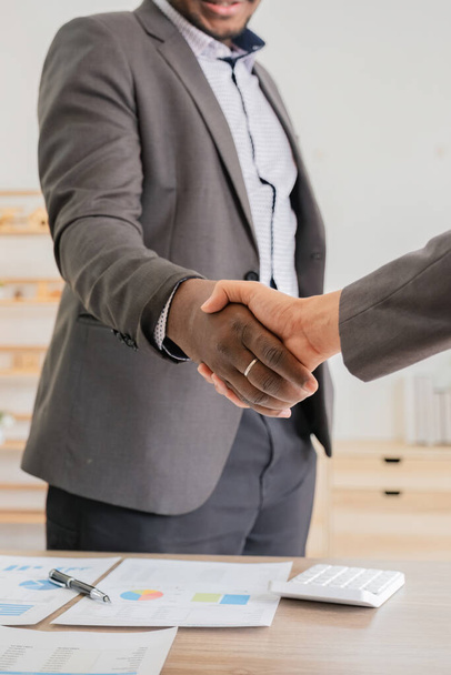 Close up of african business man and asian man shaking hands while at the office. - Photo, Image