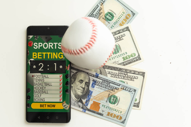 Смартфон з мобільним додатком для азартних ігор та футбольним м'ячем з грошима крупним планом. Концепція спорту та ставок. Високоякісна фотографія - Фото, зображення
