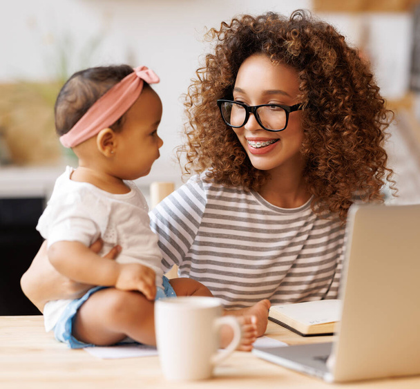 Freelance and motherhood. Happy young african american woman, self employed mother enjoying remote work from home with cute baby girl infant while sitting together in front of laptop  - Photo, Image