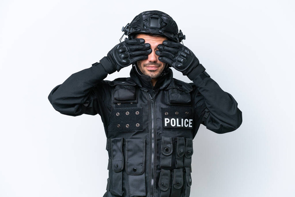 Νεαρός καυκάσιος SWAT απομονωμένος σε λευκό φόντο που καλύπτει τα μάτια με τα χέρια - Φωτογραφία, εικόνα