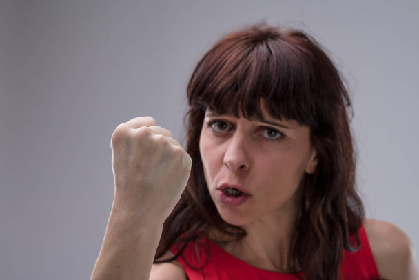 Close-up of an adult woman threatening physical violence, waving a fist near your face. Her expression insults and promises punishment for your faults. Angered, she believes in an eye for an eye - Photo, Image