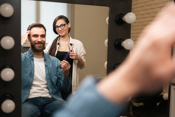 Cliente in abiti casual comunica con una donna barbiere, il maestro ha strumenti di lavoro nelle sue mani - Foto, immagini