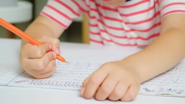 Een zesjarig jongetje leert schrijven, met de hand schrijven en close-up schrijven. - Video
