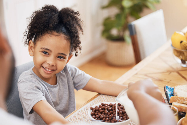 Китчен, завтрак и счастливый семейный ребенок улыбаются на утреннюю еду, еду и родители наливают молоко. Дом, счастье и маленький ребенок, молодая девушка и готовая к питанию, голодная и кушающая в Бразилии. - Фото, изображение