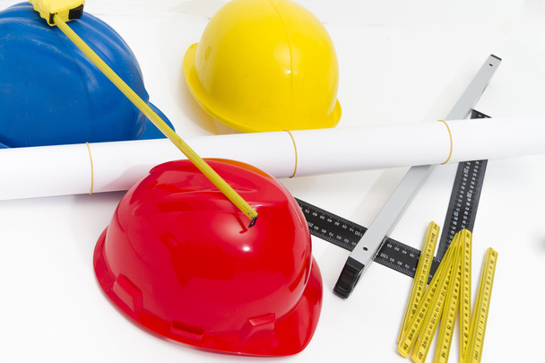 Разноцветные шлемы и инструменты для строительных чертежей и сборки
 - Фото, изображение