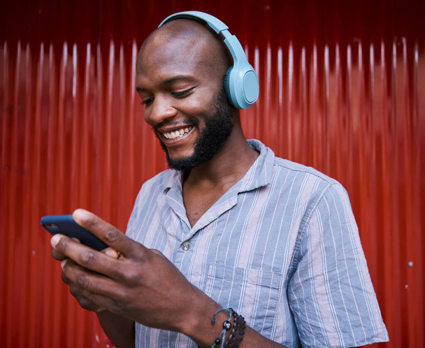 Hombre negro, smartphone y auriculares, sonríe con tecnología y escucha música o podcast. Comunicación, redes sociales y chat online, streaming de audio y suscripción con red y gen z. - Foto, imagen